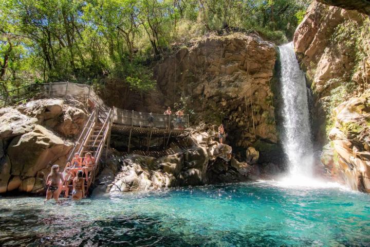 a group of people on a rock next to a waterfall